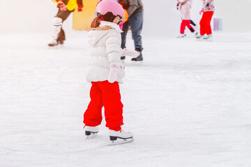 Naklejka premium Soft,Selective focus.Adorable little kid in winter clothes with protections skating on ice rink.A kid 3-5 years old, learn train, ride winter city rink, ice skating.Outdoor.Winter sport
