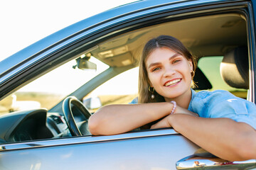 pretty woman singing while driving a car on road trip on summer day