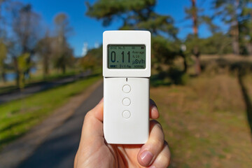 Radiometer dosimeter in hand outdoors. Measurement of ionizing radiation. Investigation of the terrain with the help of special measuring equipment. Modern problem of ecology - radioactive contaminati