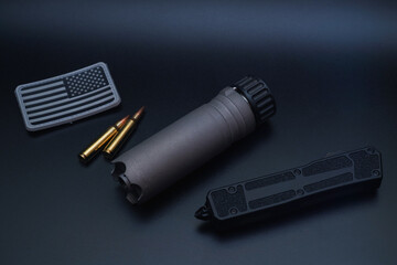 Tactical equipment.  Quick release rifle silencer, 5.56x45mm ammo, folding knife and American flag...