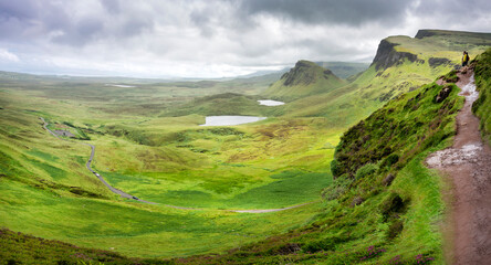 Hill walkers overlook the Quiraing and winding narrow road,from a mountainside trail. - Powered by Adobe