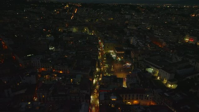 Aerial view of vehicles passing through Piazza Dante square at night. Illuminated streets and buildings in city centre. Naples, Italy