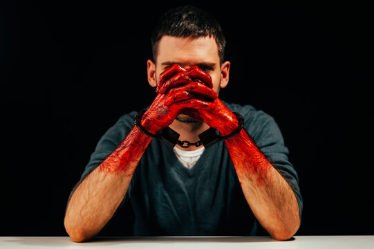 Portrait of a man with bloody hands handcuffed.