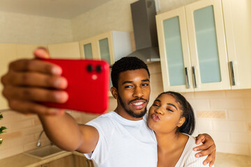 Cheerful multiethnic couple taking a selfie at the kitchen