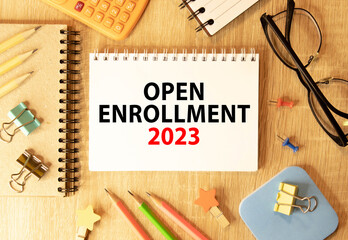 Open Enrollment. Text and a man's hand holding a black marker on a white background.