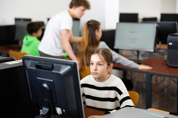 Fototapeta premium Pupils using computers at lesson, teacher teaching them in classroom
