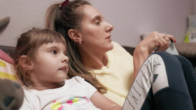 Addictive: Little girl is watching her mother playing video games