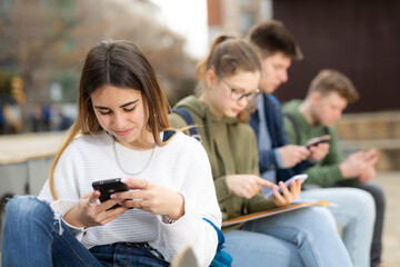 Four teenagers chatting on their smartphone on walking