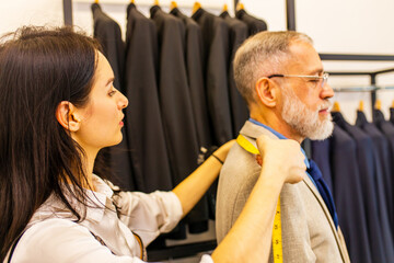 a professional tailor woman trying on a tailor-made suit for an elderly man