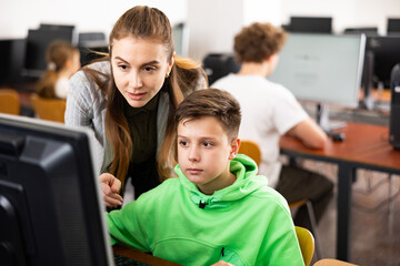 Teacher together with students conduct a lesson on computer education