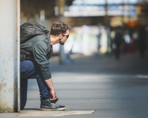 man with sunglasses tying shoes knelt down