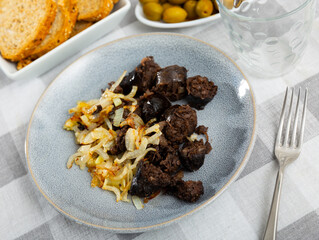 Morcilla con cebolla - fried blood sausage with onion on table. Spanish cuisine