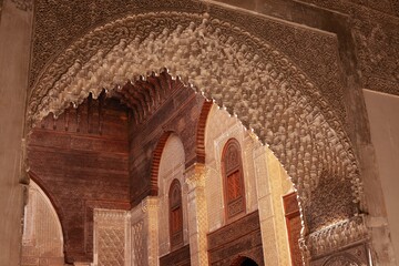 View of an orange building's interior arch of the Al-Attarine Madrasa in Marocco