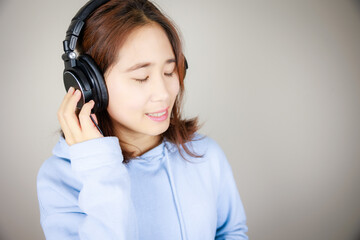 ヘッドフォンをつけて音楽を聴くアジア人女性