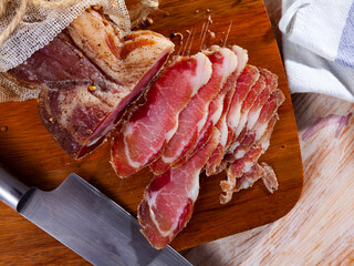 Slices of cured pork tenderloin on wooden cutting board.