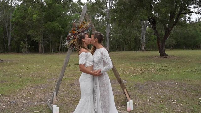 Lesbian wedding first kiss under altar in forest