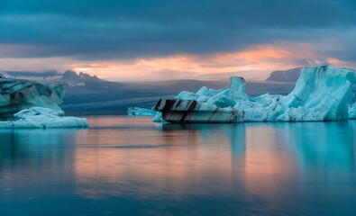 Fototapeta na wymiar jokulsarlon glacier lagoon during sunset with orange sunlight over the cloud and reflection