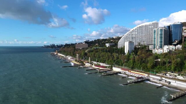 Panoramic view of parks, mountain and residential high-rise buildings in Sochi, drone shooting from a height from the sea. The coastline of the Black Sea with breakwaters.