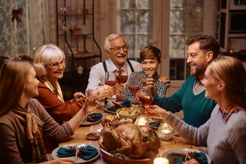Happy extended family toasting while celebrating Thanksgiving at dining table.