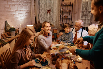 Happy woman enjoying during family meal at dining table on Thanksgiving.
