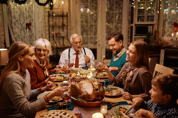 Happy multigeneration family enjoying in Thanksgiving dinner at dining table.