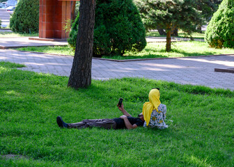 Young people relax in the summer in the park on the grass