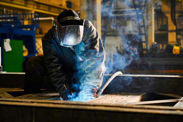 Worker with mask welds details with semi automatic machine