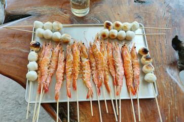 Naklejka premium Grilled Shrimp Skewers, Fish Ball Skewers Grilled. Homemade BBQ Seafood. Charcoal Grilled Camping dish.