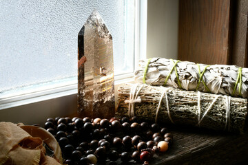 Large smoky quartz tower with two healing smudge sticks and mala necklace on an old wooden window...