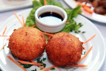 Potato balls with sauce on the dinner plate.