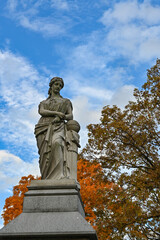 Fototapeta na wymiar A statue of a woman in a cemetery in the autumn