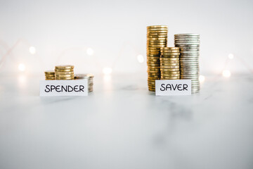 Saver vs spender texts in front of big and small stacks of coins. Concept  of money, abundance and...