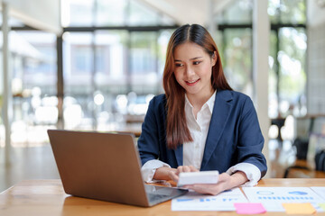 Obraz na płótnie Canvas Portrait of smiling Asian business woman enjoying work ideas sitting on laptop at office.