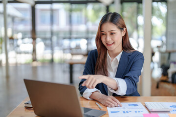 Fototapeta na wymiar Portrait of smiling Asian business woman enjoying work ideas sitting on laptop at office.