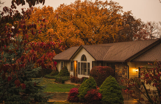 View Of Suburban Midwestern House On Rainy Autumn Day; Colorful Trees In Front Yard And Background; View From The Street