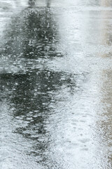wet asphalt sidewalk with puddles during rain