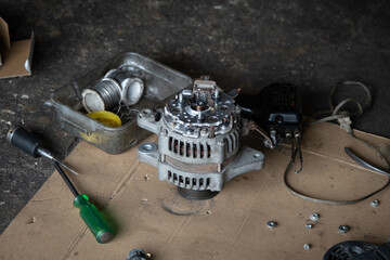 The car's dynamo was placed on the floor awaiting repair in the garage.