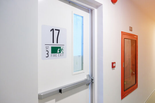 Fire extinguisher system on the wall with Fire Exit door sign for emergency. Stairwell fire for escape in building or apartment