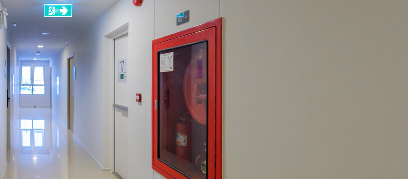 Fire extinguisher system on the wall with Fire Exit door sign for emergency. Stairwell fire for escape in building or apartment
