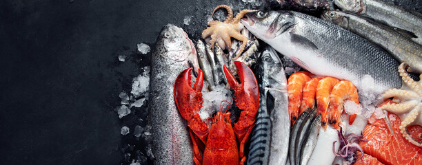 Fresh fish and seafood assortment on black background, fish market. Healthy diet eating concept....