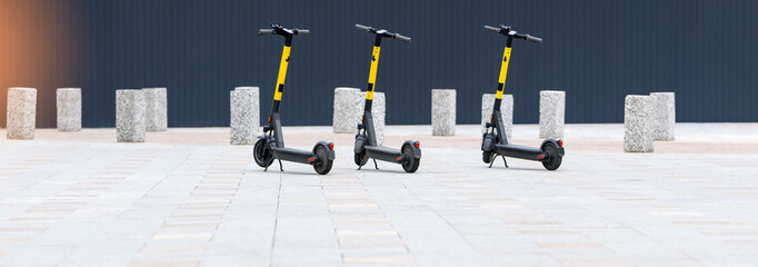 Electric scooters are parked in the city. Banner