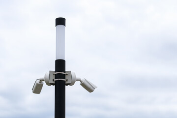 Outdoor security camera on a pole against the sky. Horizontal photo. Optics