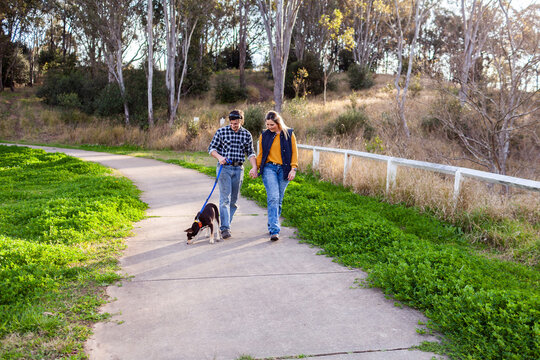 Happy young couple in their twenties out walking their Australian Kelpie dog
