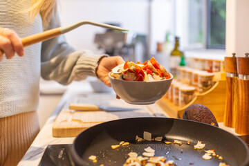 Close up shot of a woman serving food into a bowl at home