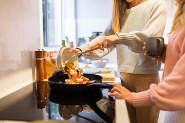 Two women in the kitchen cooking together, serving dinner
