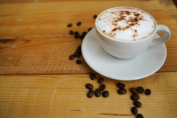 Hot cappuccino in white cup with wooden background,coffee is a popular drink all over the world.