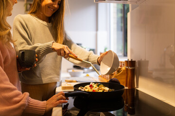 Two women cooking together and serving the meal at home