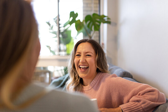 Close up shot of a laughing woman wearing pink sweatshirt talking to her partner