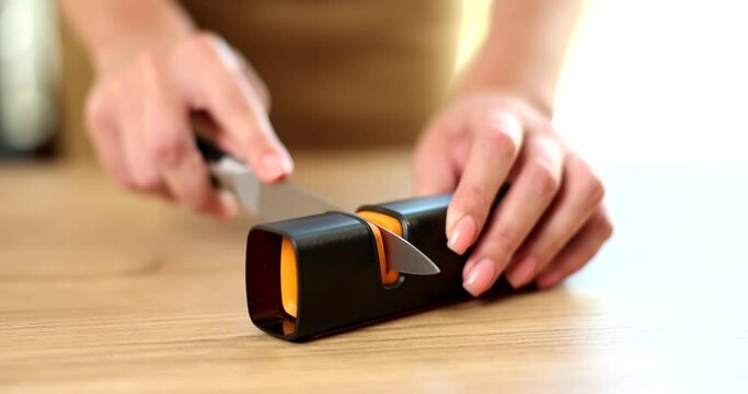 Sharpening stainless steel kitchen knife with knife sharpener closeup