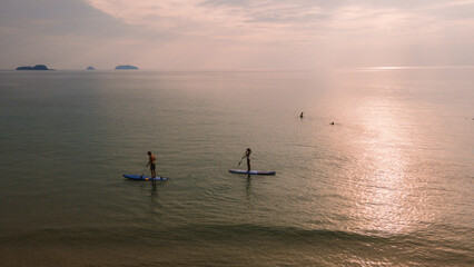 A couple of men and women paddling at a sup board in Koh Chang Thailand during sunset. stand-up...